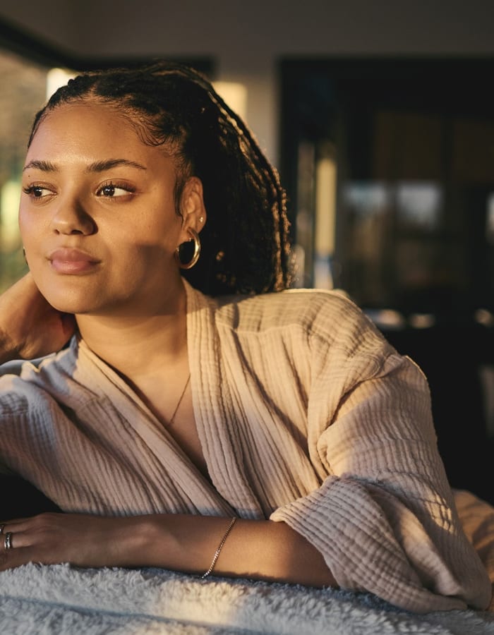 A woman sitting quietly, looking away in thought.