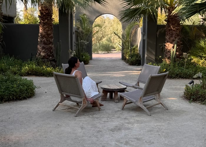 Chairs around a low table in a palm courtyard.